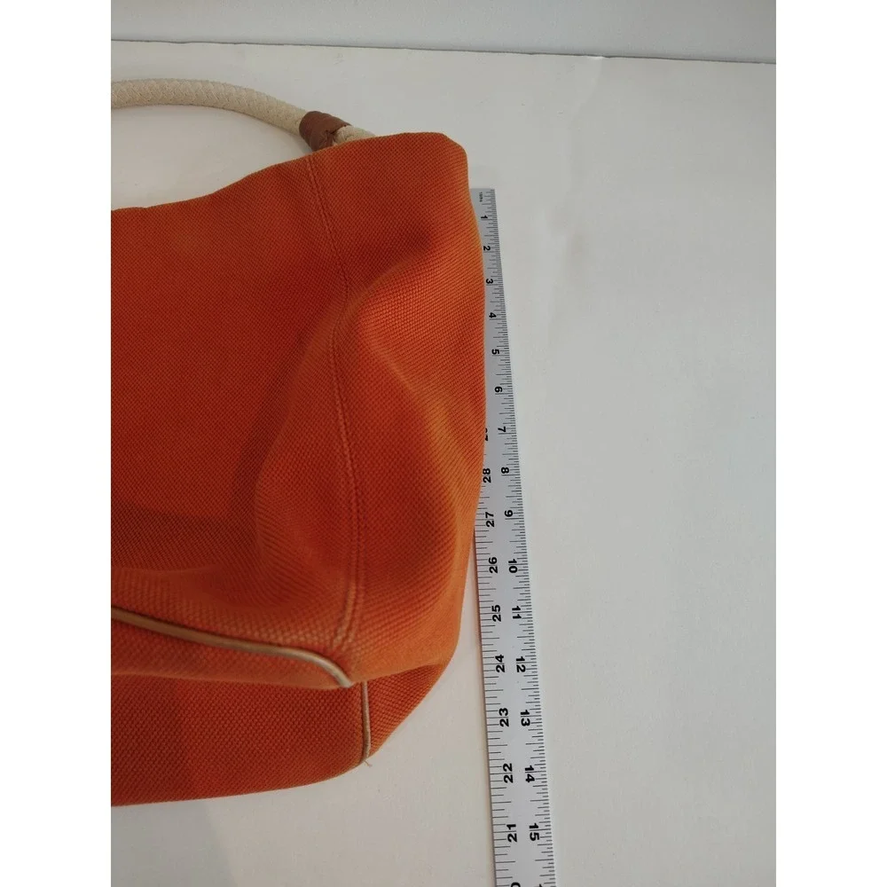 Michael Kors Marina hobo bag features an orange canvas body with braided rope...
